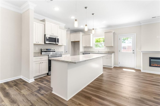 kitchen with crown molding, appliances with stainless steel finishes, a kitchen island, and white cabinetry