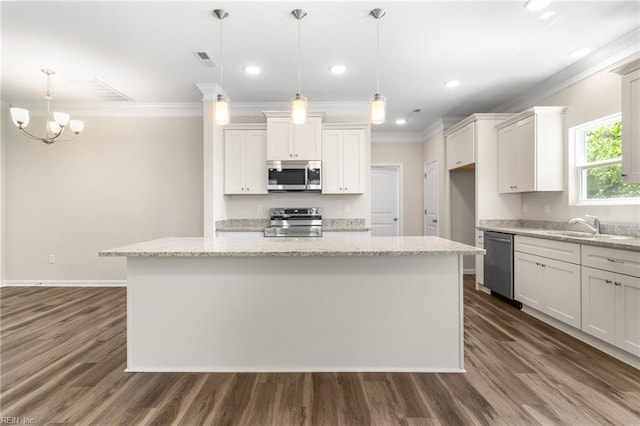 kitchen with a center island, ornamental molding, a sink, and stainless steel appliances