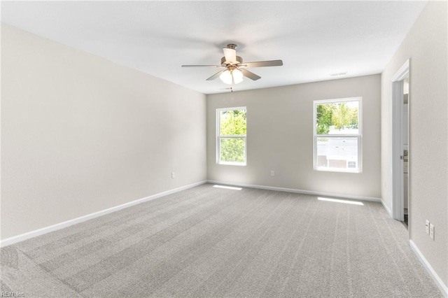 unfurnished room with baseboards, a ceiling fan, a wealth of natural light, and light carpet