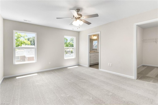 unfurnished bedroom featuring carpet floors, baseboards, a walk in closet, and visible vents