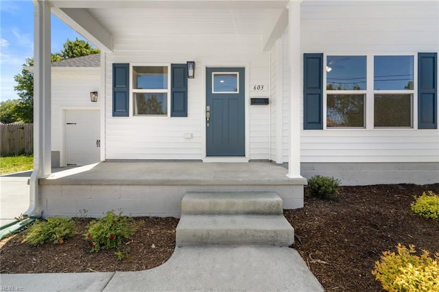 property entrance featuring covered porch and fence