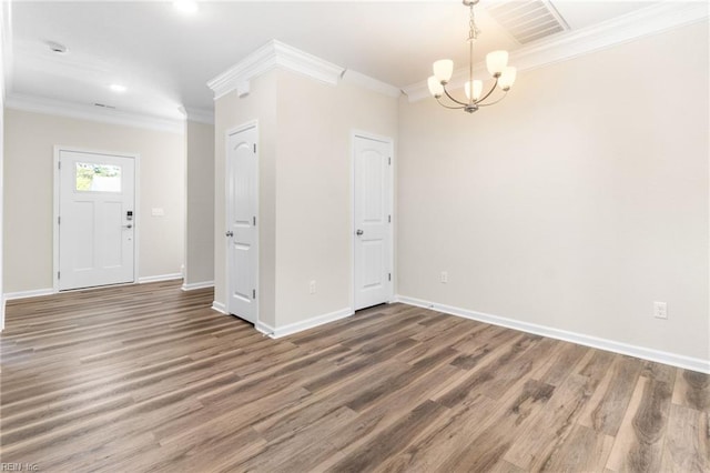 entryway featuring crown molding, a notable chandelier, baseboards, wood finished floors, and visible vents