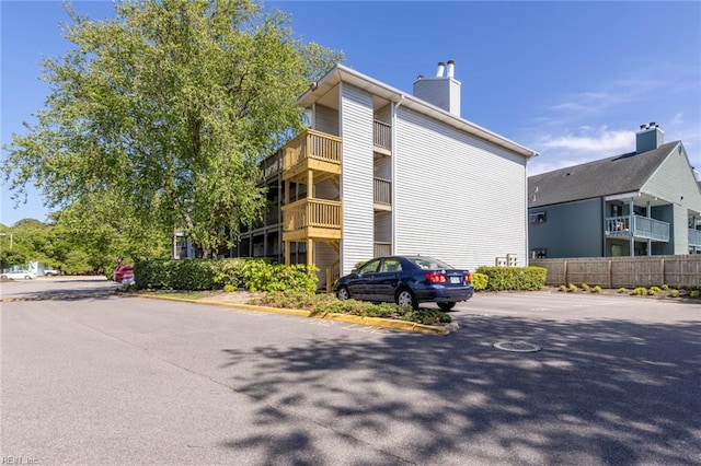 view of building exterior featuring uncovered parking and fence