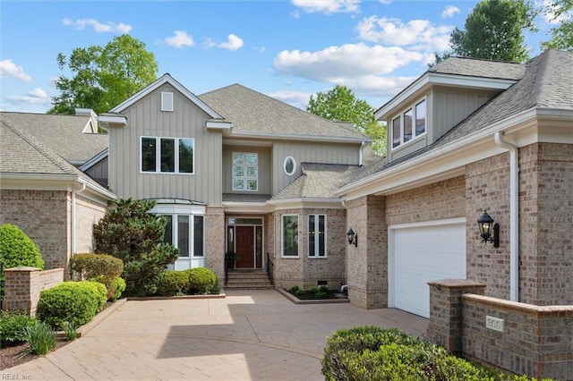 view of front facade with brick siding, a shingled roof, board and batten siding, and driveway