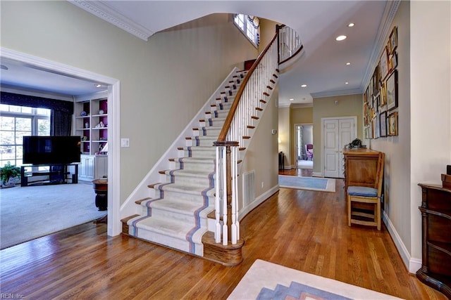 staircase with baseboards, ornamental molding, and wood finished floors
