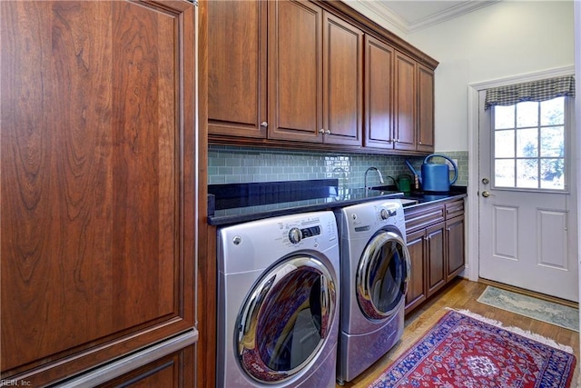 laundry room featuring independent washer and dryer, crown molding, light wood-type flooring, cabinet space, and a sink