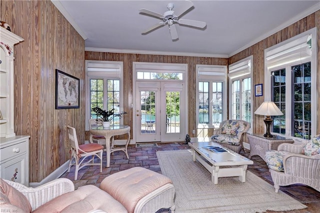 interior space with ornamental molding, brick floor, wood walls, and ceiling fan