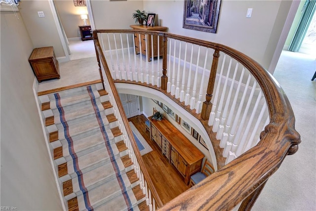 stairway featuring baseboards, carpet, and arched walkways