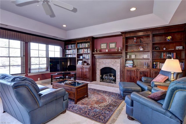 carpeted living room featuring a ceiling fan, a tray ceiling, recessed lighting, and a fireplace
