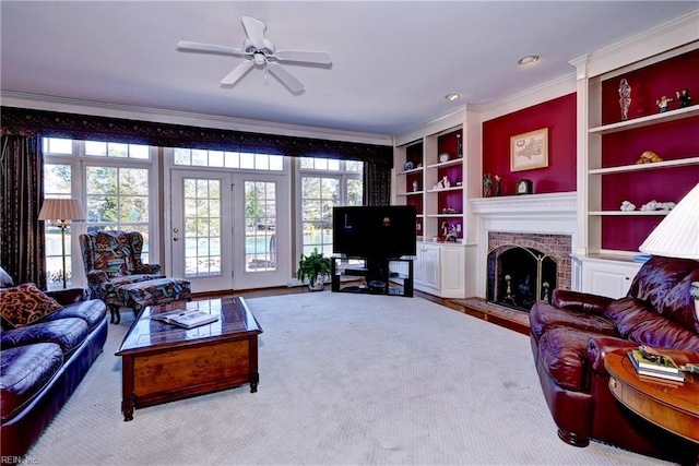 living area featuring crown molding, built in features, a fireplace, and a ceiling fan