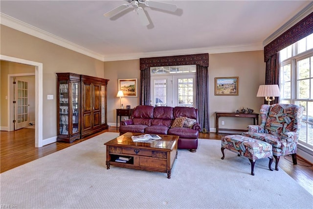 living area featuring crown molding, a ceiling fan, baseboards, and wood finished floors