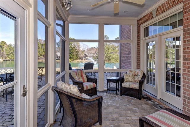 sunroom / solarium featuring a ceiling fan and a water view