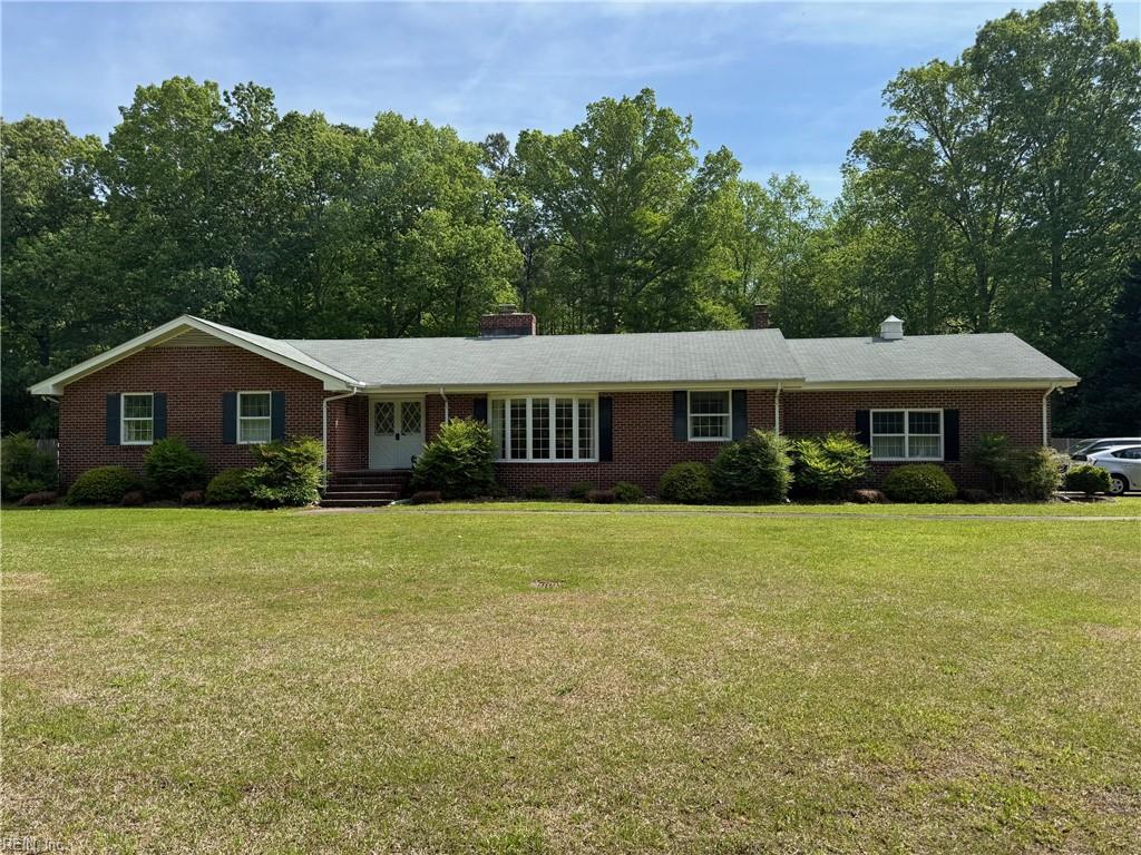 ranch-style house featuring brick siding, a chimney, and a front yard
