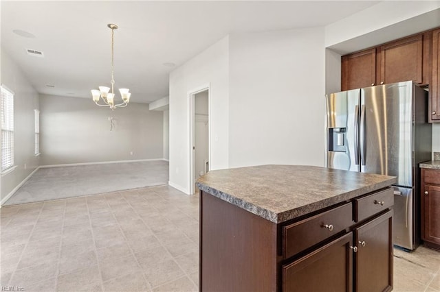kitchen featuring a notable chandelier, stainless steel fridge, open floor plan, a kitchen island, and pendant lighting