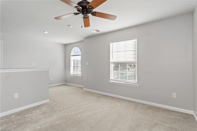 carpeted spare room with a ceiling fan, baseboards, and visible vents
