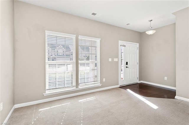 carpeted entryway with baseboards, a wealth of natural light, and visible vents