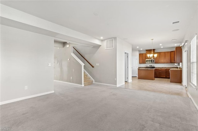 unfurnished living room with baseboards, light carpet, recessed lighting, and a chandelier