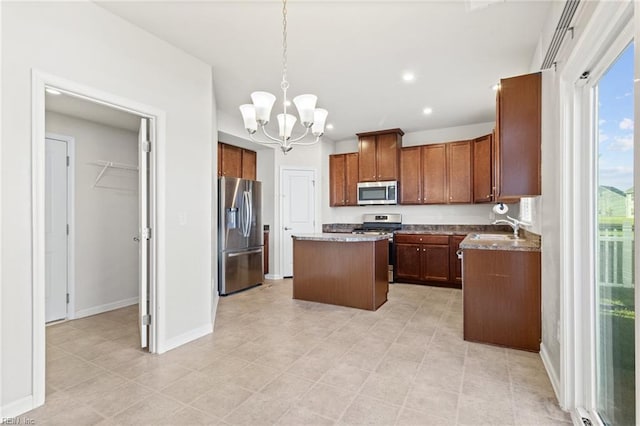 kitchen with a kitchen island, appliances with stainless steel finishes, a sink, baseboards, and a notable chandelier