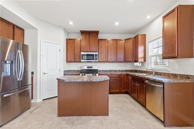 kitchen featuring dark countertops, appliances with stainless steel finishes, a sink, light tile patterned floors, and a kitchen island
