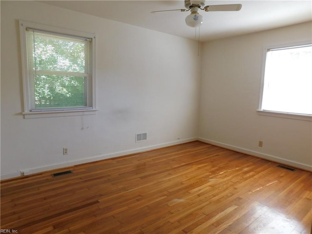 unfurnished room with ceiling fan, visible vents, plenty of natural light, and light wood-type flooring