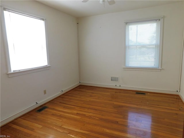 spare room with visible vents, a healthy amount of sunlight, and wood finished floors