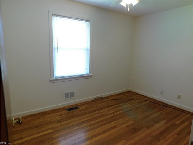 empty room featuring a ceiling fan, baseboards, visible vents, and wood finished floors
