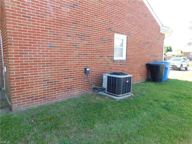 view of side of property with central air condition unit, a lawn, and brick siding