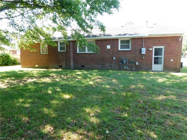 back of house featuring a yard, brick siding, and crawl space