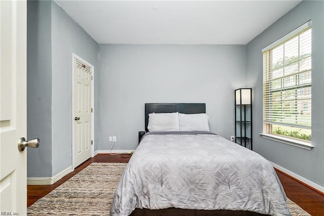 bedroom with baseboards and dark wood-style flooring