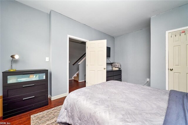 bedroom with baseboards, vaulted ceiling, and dark wood-style floors