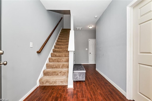 stairs with baseboards, wood finished floors, and visible vents