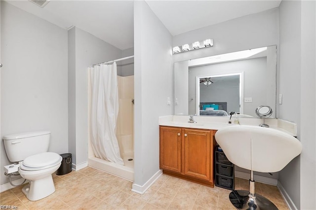 ensuite bathroom with baseboards, a sink, a stall shower, and toilet