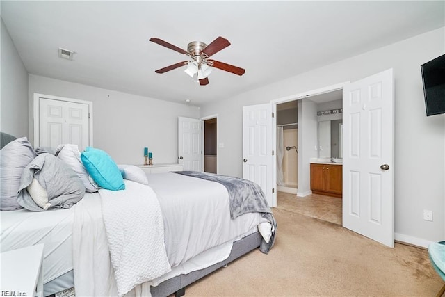 bedroom with a ceiling fan, light colored carpet, visible vents, baseboards, and ensuite bath