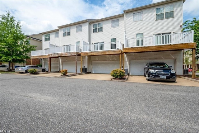 rear view of house featuring central air condition unit, driveway, and a garage