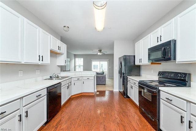 kitchen with black appliances, dark wood-style floors, and white cabinetry