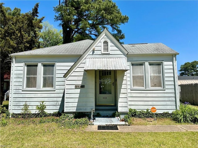 bungalow-style home with a shingled roof and a front lawn