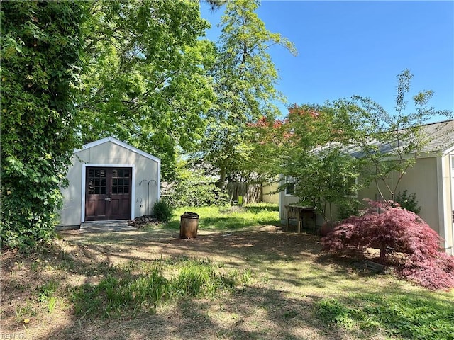 view of yard featuring fence, a storage unit, and an outbuilding
