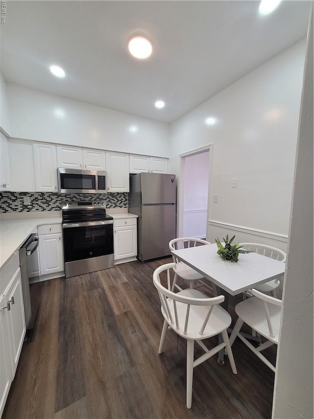 kitchen with backsplash, stainless steel appliances, dark wood-style floors, and white cabinetry