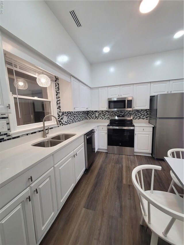 kitchen with a sink, appliances with stainless steel finishes, backsplash, and light countertops