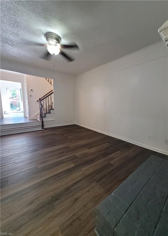 spare room featuring a ceiling fan, a textured ceiling, dark wood-style floors, and stairway
