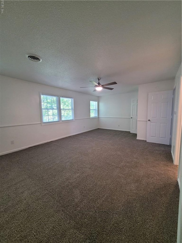 unfurnished room with visible vents, dark carpet, baseboards, a textured ceiling, and a ceiling fan