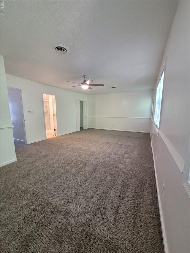 carpeted empty room with ceiling fan, visible vents, and baseboards