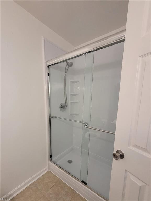 full bathroom with baseboards, tile patterned floors, and a shower stall