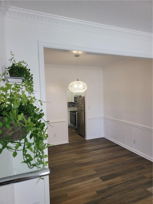 unfurnished dining area featuring crown molding, dark wood-style flooring, and baseboards