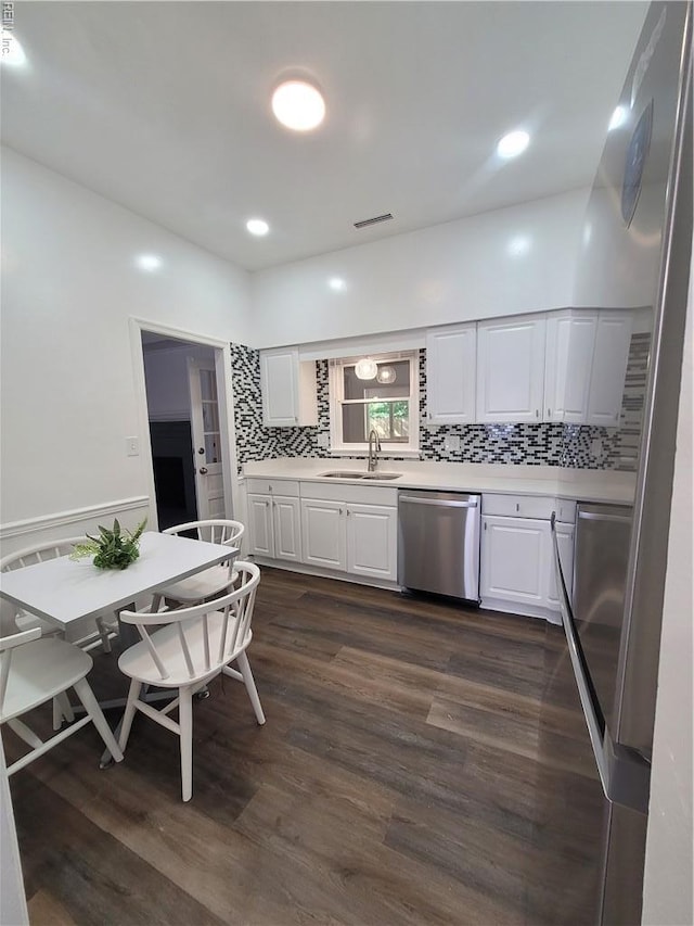 kitchen featuring stainless steel dishwasher, a sink, white cabinetry, and light countertops