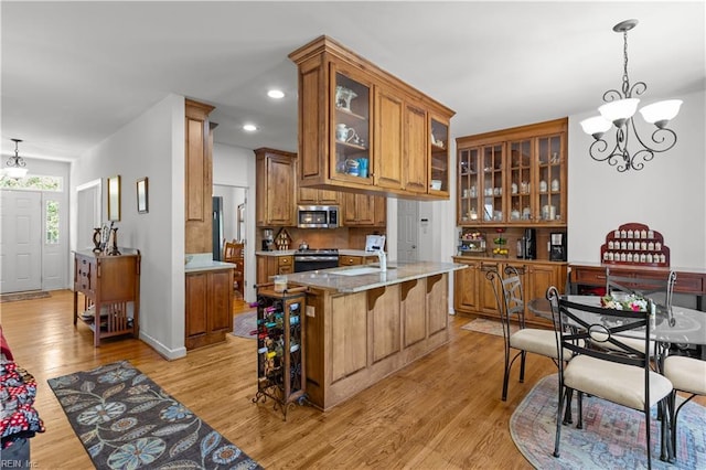 kitchen with stainless steel microwave, a kitchen bar, brown cabinetry, and light wood-style floors