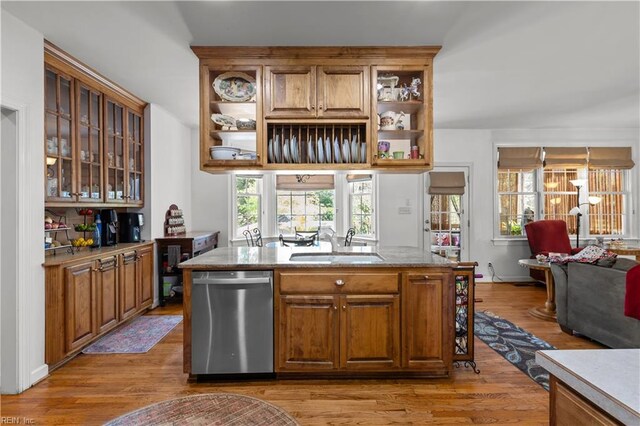 kitchen with stainless steel dishwasher, open shelves, light wood-type flooring, brown cabinets, and a sink