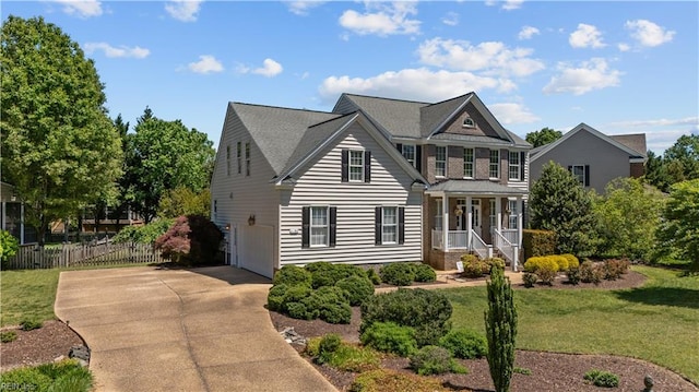 traditional-style home with fence, an attached garage, driveway, and a front yard