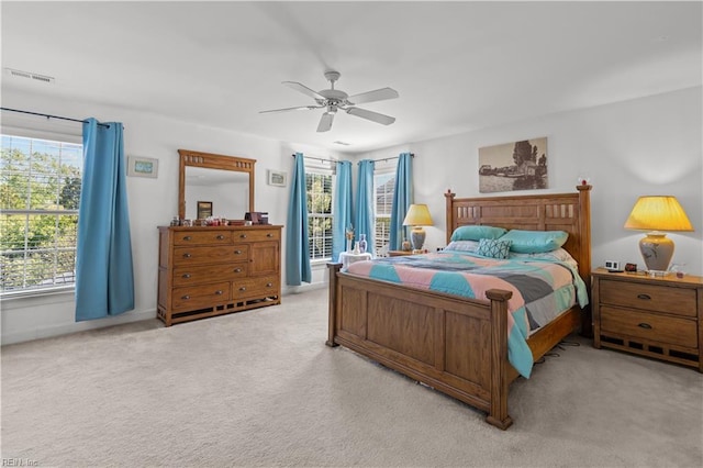 bedroom with visible vents, ceiling fan, multiple windows, and light carpet