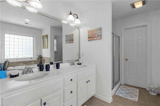 bathroom with double vanity, visible vents, a shower stall, and a sink